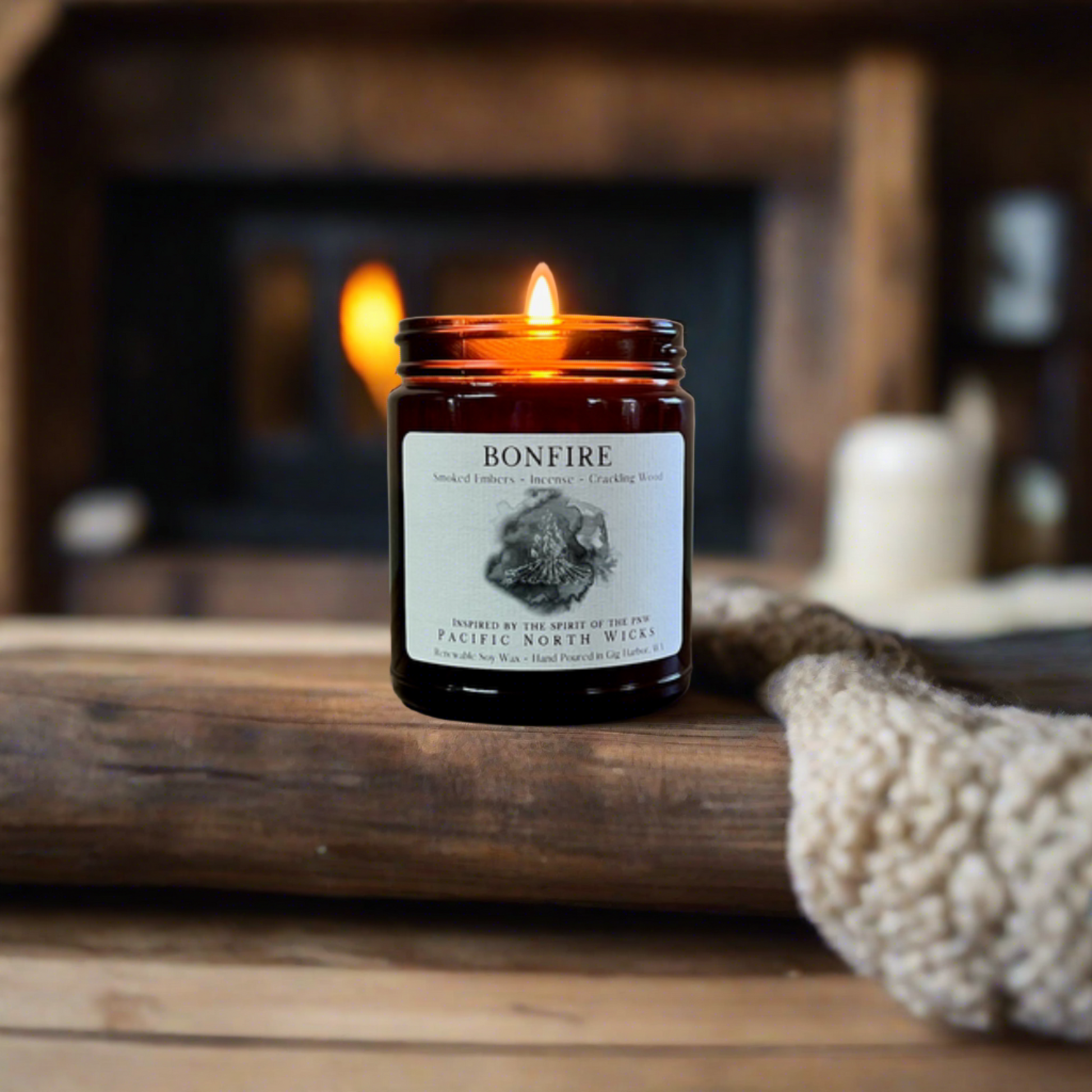 Fireside Candle Burning in cozy cabin setting with Fireplace in background surrounded by cozy blankets in winter