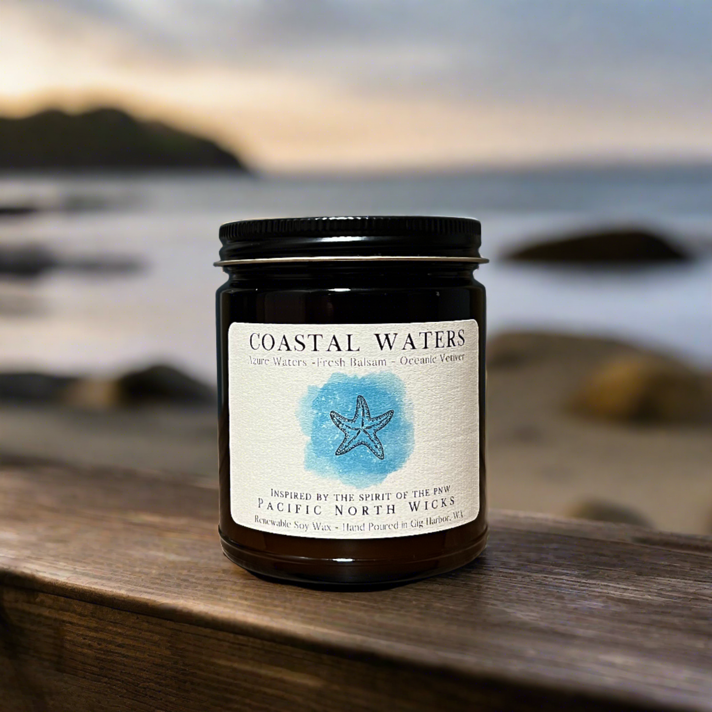 Coastal Candle with Seaside in background at sunset. Handmade in PNW with soy wax and features 9oz amber jar with black metal lid.