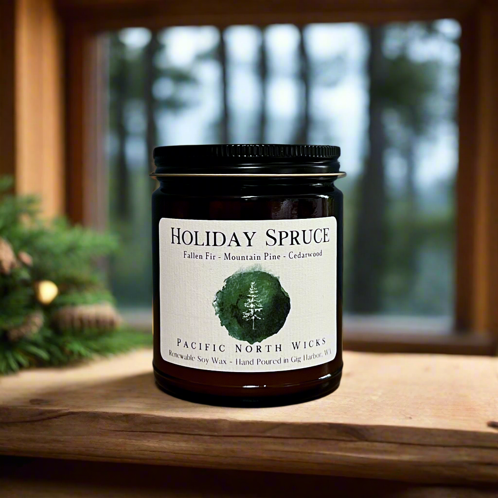 Holiday Spruce candle with scent notes of fallen fir, mountain pine, and cedarwood. Amber jar candle is set in rustic forest cabin amongst the trees.