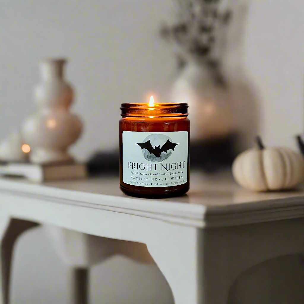 Halloween candle lit with modern fall decor including white pumpkins.