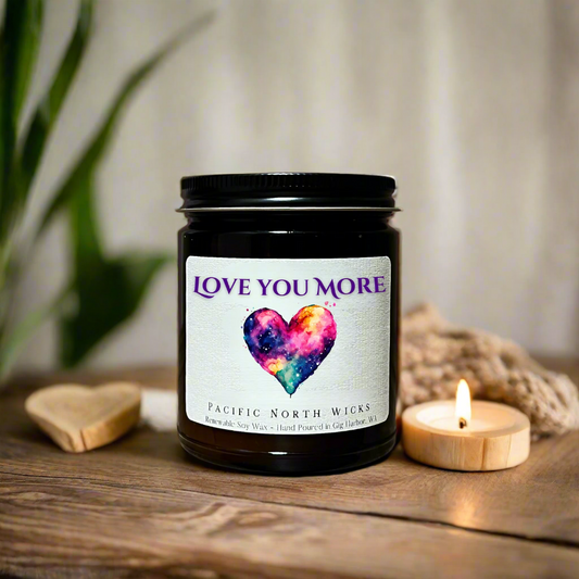Amber jar candle with Love you More label in cozy setting with neutral color tones