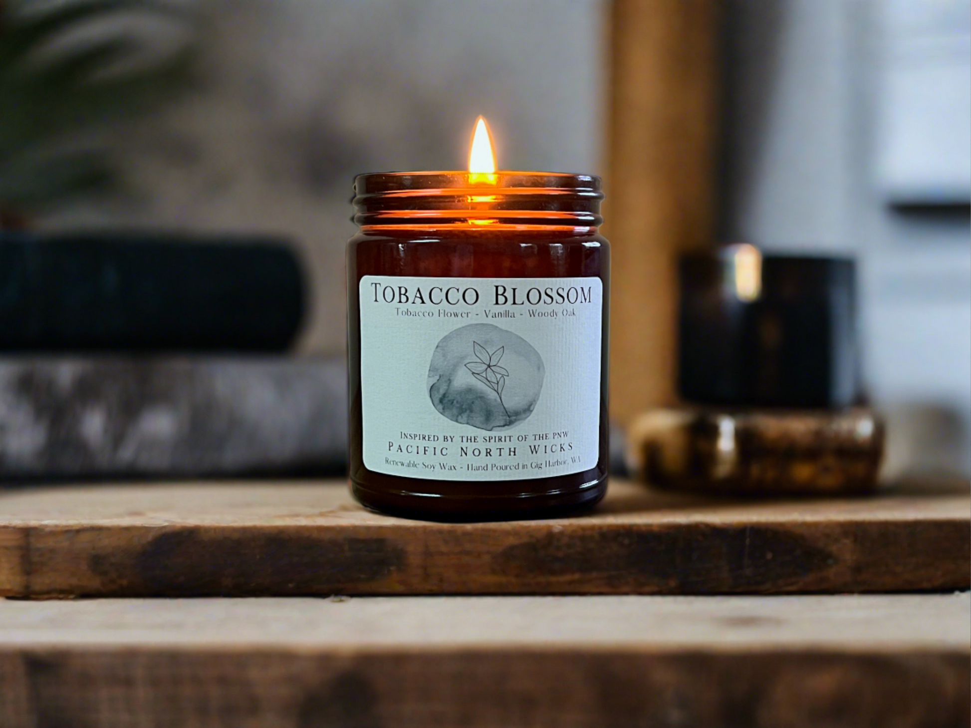Tobacco Blossom candle lit in cozy setting with warm and rustic wood tones.