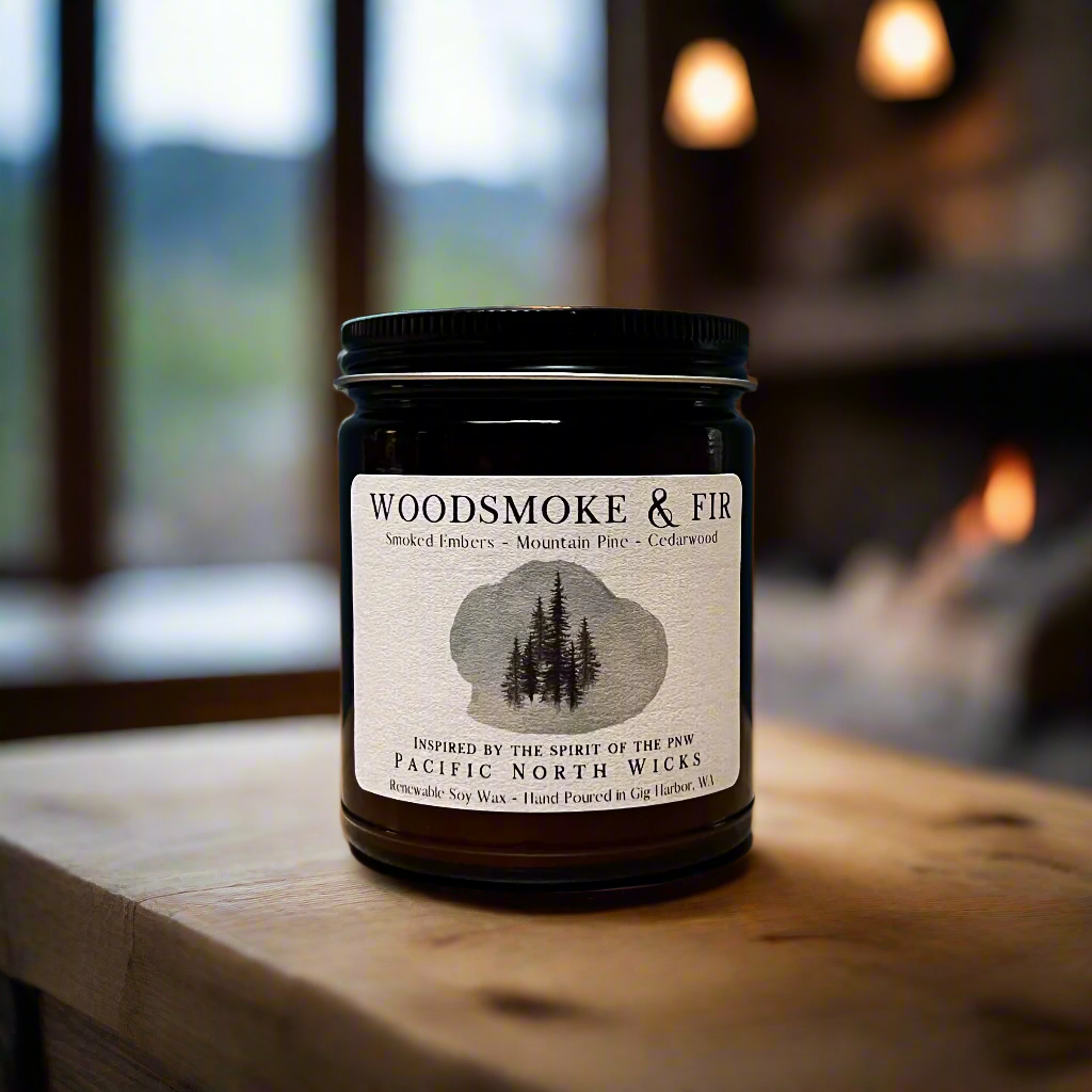 Amber jar candle with Woodsmoke & Fir label with scent notes of smoked embers, mountain pine, and cedarwood.