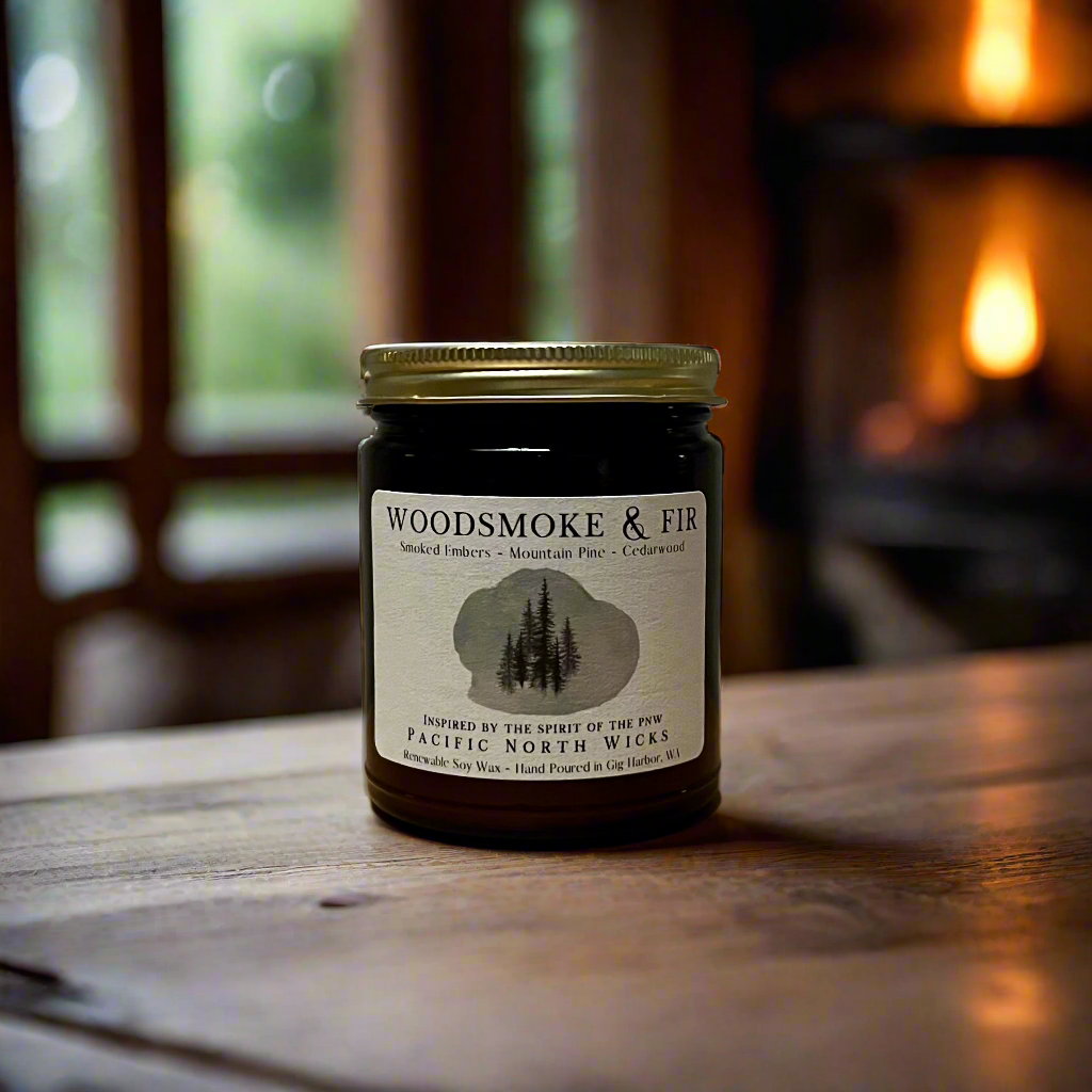 Masculine scented candle with gold lid in forest cabin setting.