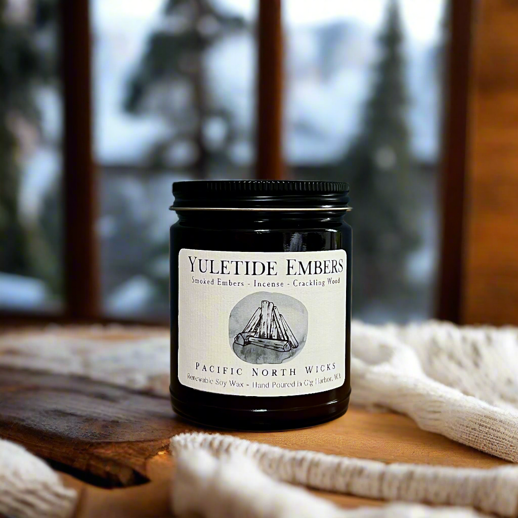 Holiday candle with Yuletide Embers label with scent notes of smoked embers, incense, and crackling wood.